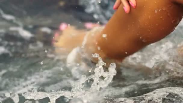 Attractive young woman with pink nails , wearing black bikini , sitting on the stone. - Filmagem, Vídeo