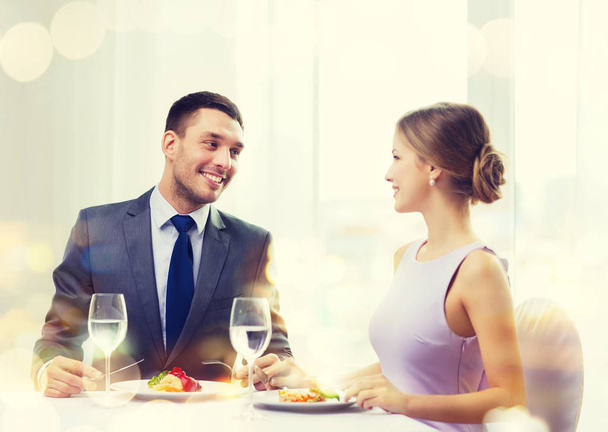 smiling couple eating main course at restaurant - Fotó, kép