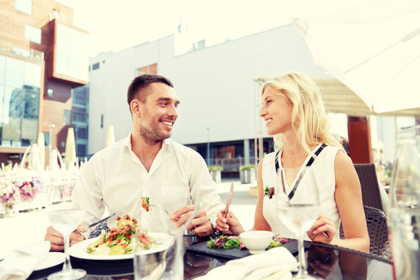 happy couple eating dinner at restaurant terrace - 写真・画像