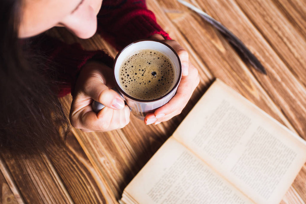 jeune femme en pull rouge tenant une tasse de café et lisant un livre
 - Photo, image
