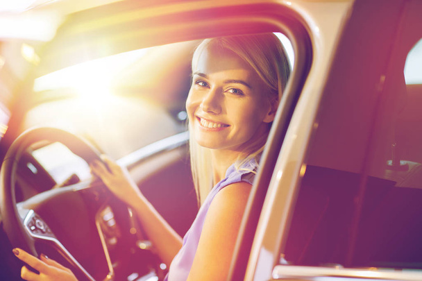 happy woman inside car in auto show or salon - Foto, afbeelding
