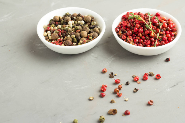 a mixture of peppers and pink peppercorns in white plates - Photo, Image