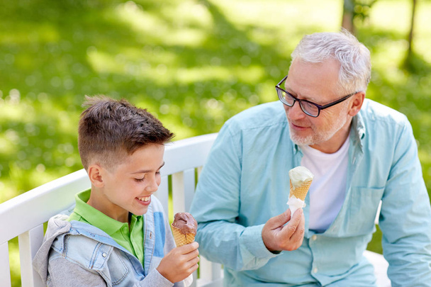 old man and boy eating ice cream at summer park - Foto, Imagen