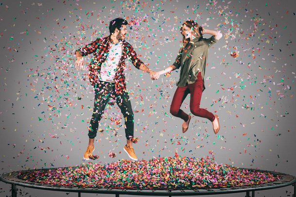 cheerful couple jumping on trampoline  - Фото, зображення