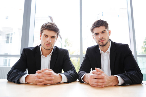 Two serious young businessmen sitting in office - Fotó, kép