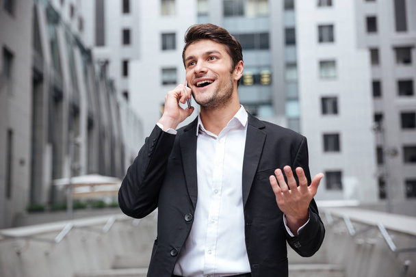 Happy young businessman talking on mobile phone in the city - Fotoğraf, Görsel
