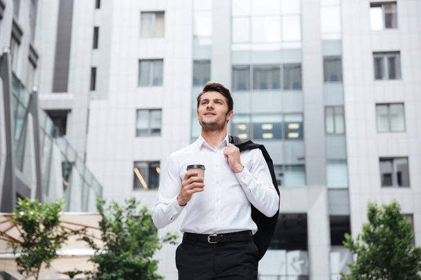 Businessman walking and drinking take away coffee outdoors - Photo, Image