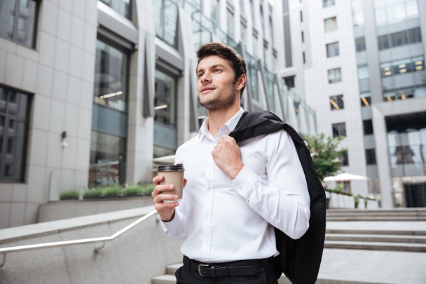 Businessman with jacket and coffee walking near business center - Фото, зображення