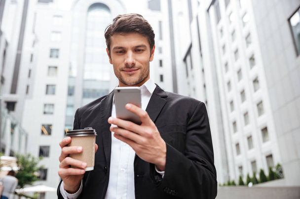 Businessman using cell phone and drinking coffee in the city - Foto, Bild