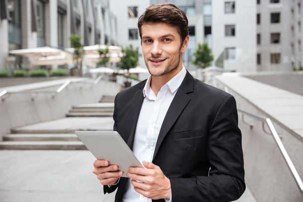 Attractive young businessman using tablet near business center - Fotó, kép