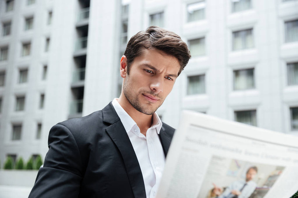 Businessman reading newspaper in the city - 写真・画像