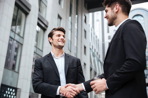 Two cheerful young businessmen shaking hands - 写真・画像