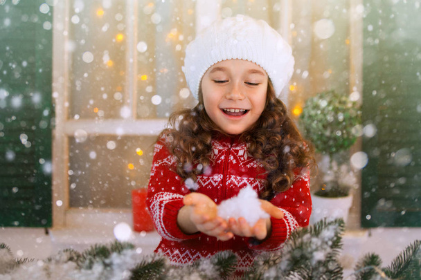 Feliz niña extiende su mano para coger copos de nieve que caen
. - Foto, Imagen