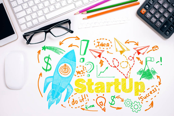 Top view of office desktop with colorful rocket ship sketch and other items. Startup concept - Photo, Image