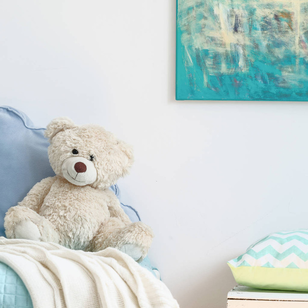 Beige teddy bear on a blue bed - Foto, Imagen