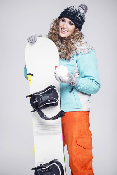 Young beautiful woman in winter clothes and snowboard - Zdjęcie, obraz