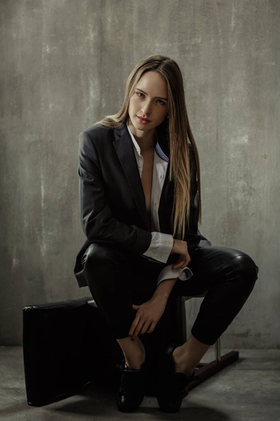The girl in classic jacket, blouse and leather pants sits on a b - Fotó, kép