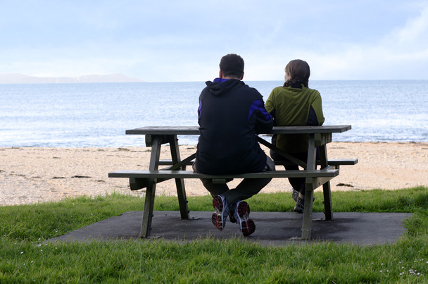 Jeune siège de couple sur les côtés opposés du banc du parc
. - Photo, image