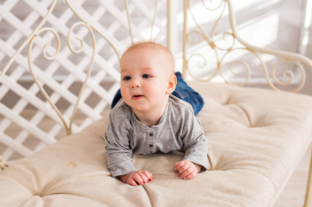 entzückender kleiner Junge im beigen, sonnigen Schlafzimmer. Neugeborenes entspannt sich. Kinderkrippe für Kleinkinder. Textil für Kinder. Familienmorgen zu Hause. Neugeborenes - Foto, Bild
