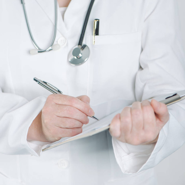 Doctora escribiendo en portapapeles papel en blanco
 - Foto, Imagen