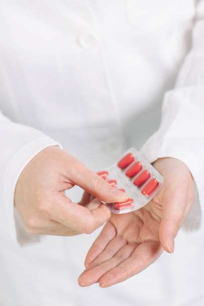 Жінка-лікар пропонує червоні таблетки пацієнту
 - Фото, зображення