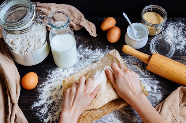 female hands preparing dough in the kitchen. Baking ingredients on the wooden table - Φωτογραφία, εικόνα