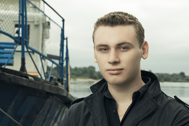 Portrait of man standing on the river bank with ship in backgrou - Foto, imagen
