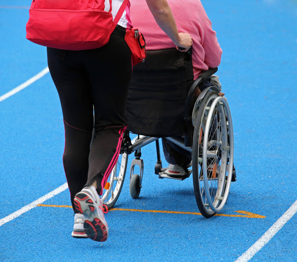 wheelchair with an attendant on the athletic track during the sp - Photo, Image