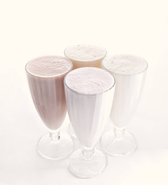 четыре стакана различных молочных коктейлей шоколад, клубника и ваниль изолированы на белом фоне
 - Фото, изображение