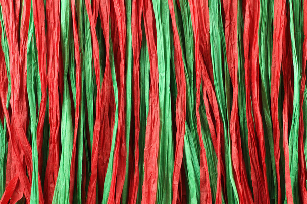 Φόντο - κόκκινο και πράσινο χαρτί Ραφία λωρίδες βρίσκεται σε παράλληλες γραμμές - Φωτογραφία, εικόνα