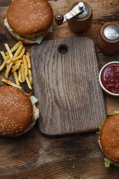 Jídlo strany tabulky koncept. Grilovací klobása sendviče s dvěma hamburger, smažené brambory a různé omáčky servírované na rustikální stůl z výšky. - Fotografie, Obrázek