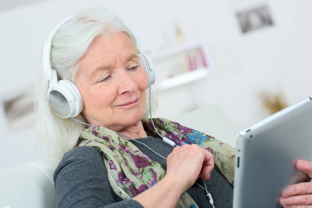 Mulher sênior feliz ouvindo música no tablet digital
 - Foto, Imagem