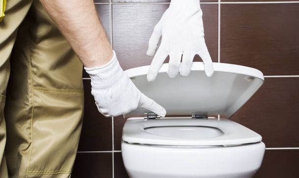 Plumber showing problem area of toilet - Zdjęcie, obraz
