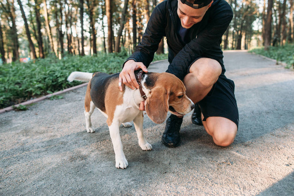 Fitness hombre en ropa deportiva con su perro en el bosque
. - Foto, Imagen