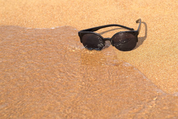sluneční brýle a písčité pobřeží s vlnou - Fotografie, Obrázek
