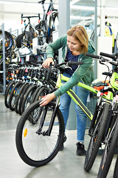 Woman testing bike in sport store - Zdjęcie, obraz