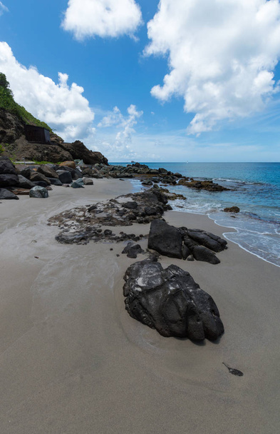 Grandes rochas na areia que levam ao mar
 - Foto, Imagem