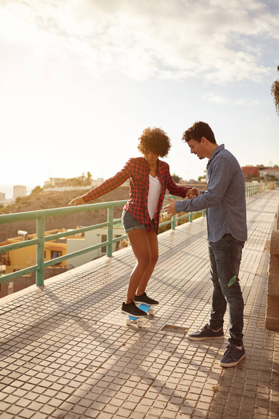Boyfriend helping girl to ride skateboard  - Fotó, kép