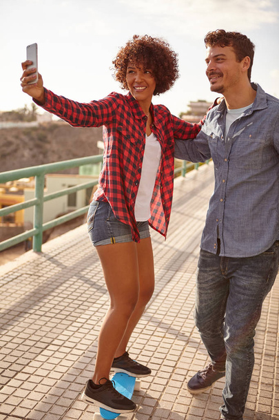 Young couple taking selfie on skateboard - Photo, Image