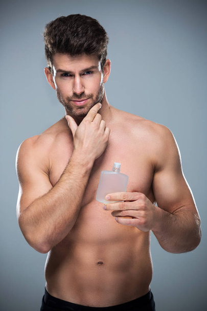 Man holding up bottle of perfume - Φωτογραφία, εικόνα