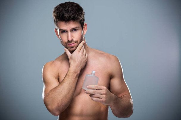 Man holding up bottle of perfume - Foto, Imagem