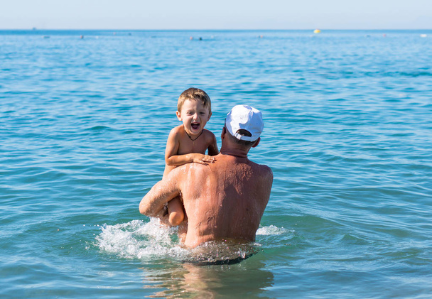 Família feliz. Sorrindo avô e neto brincando no mar
. - Foto, Imagem