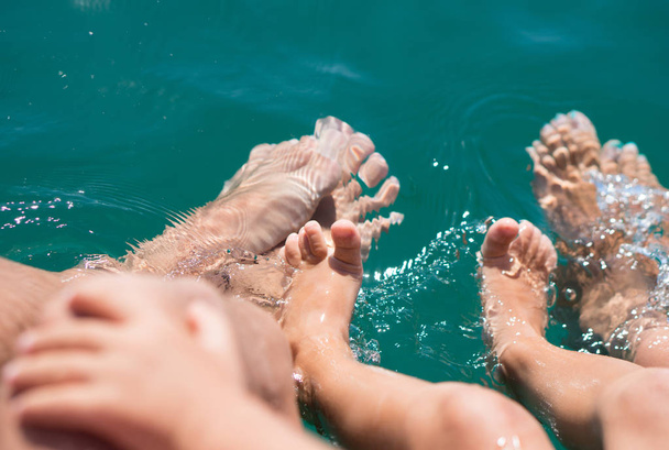 Csupasz lábak, a víz, a tengeri fiú, anya, apa. Pozitív emberi érzelmek, érzések, öröm. - Fotó, kép