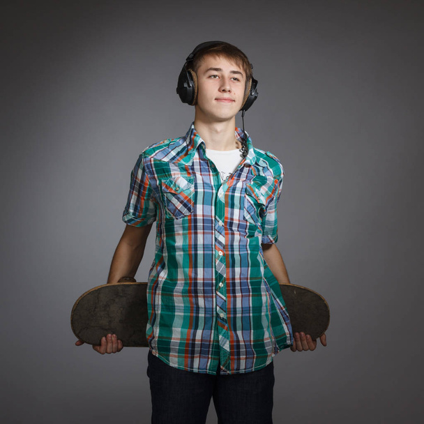 The guy is a teenager with skate boarding and headphones. - Zdjęcie, obraz