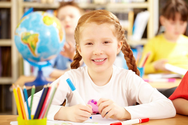 punatukkainen koulutyttö istuu luokkahuoneessa
 - Valokuva, kuva
