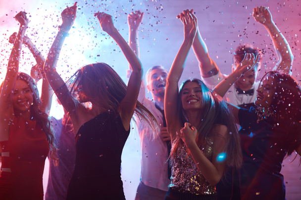 Extatisch vrienden dansen in de confetti-regen  - Foto, afbeelding