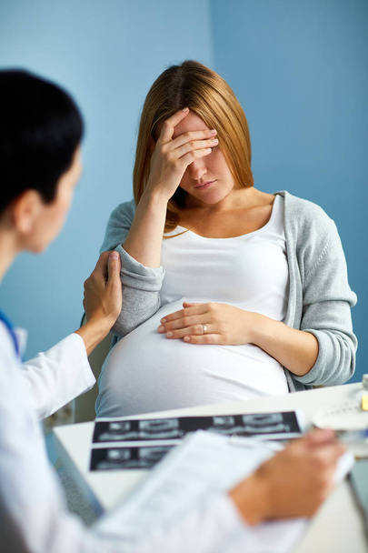 Акушер поддерживает грустную беременную женщину
  - Фото, изображение