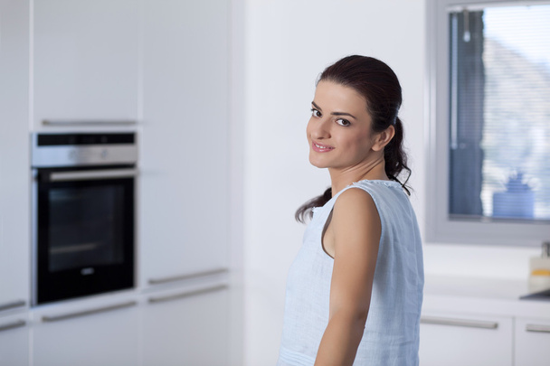 mooie lachende vrouw kijken naar ons in de keuken - Foto, afbeelding