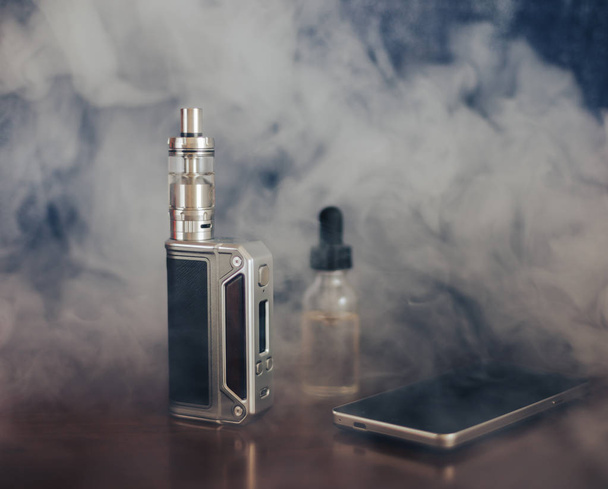 Vape devices, E-cigarette for vaping, liquid in the bottle and mobile phone  - Photo, Image