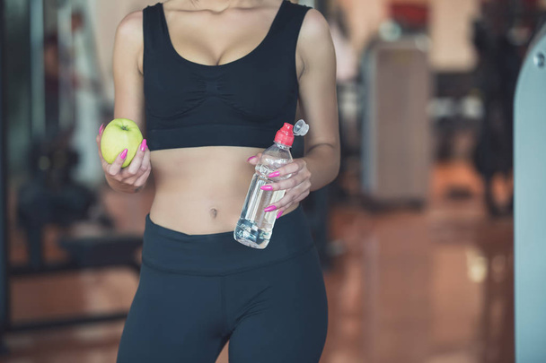 sports lady holding an apple and a bottle of water - Foto, Imagen